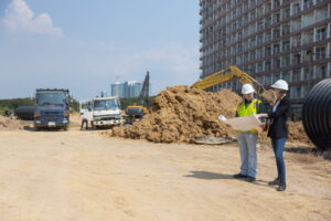 Construction site waste management plan with dumpsters, recycling bins, and workers sorting debris.